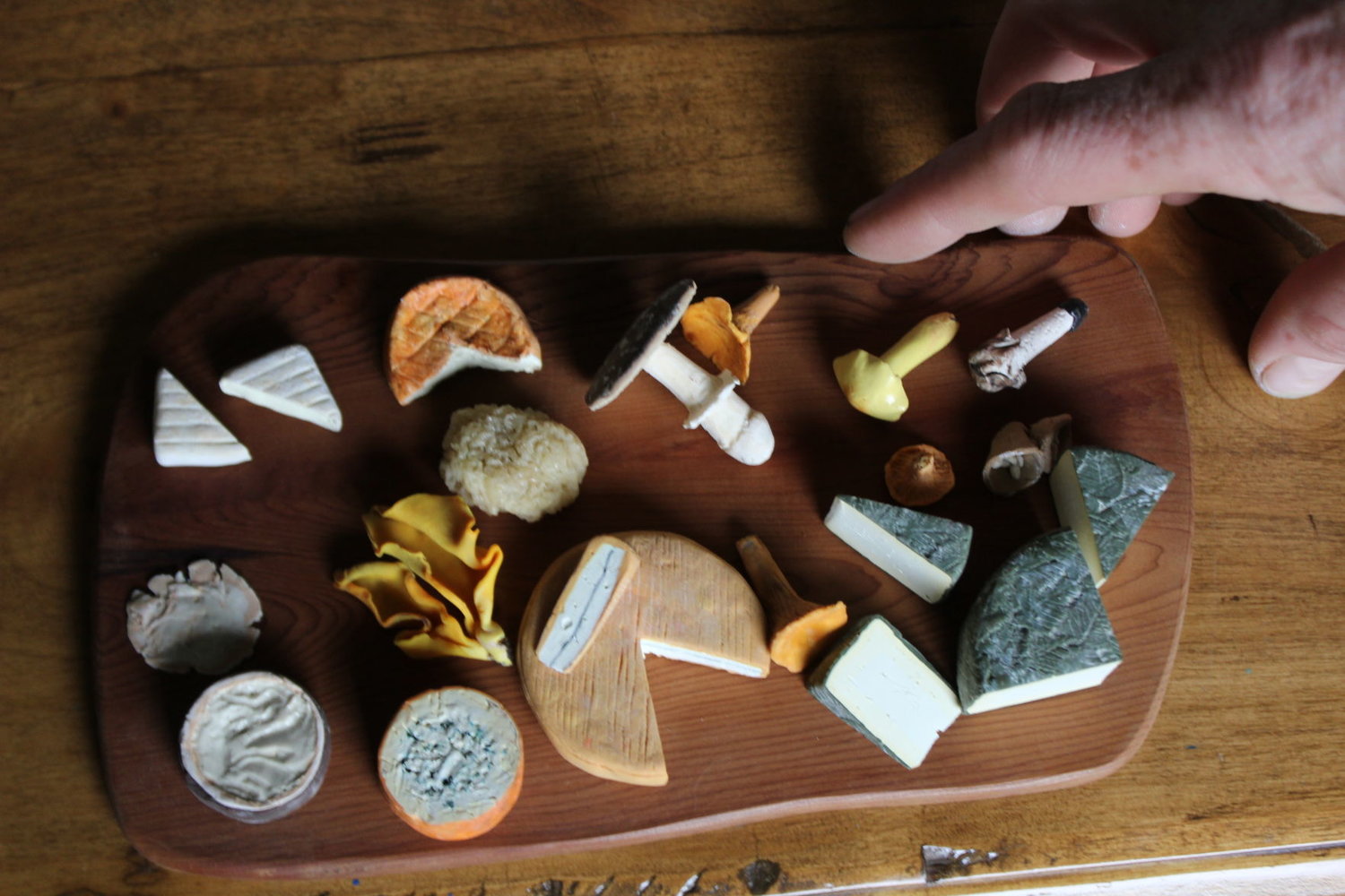 Artist Dylan Stanfield draws from his knowledge as a cheesemaker to create his miniatures. Even though they are made of clay and the size of a quarter, they look edible. 