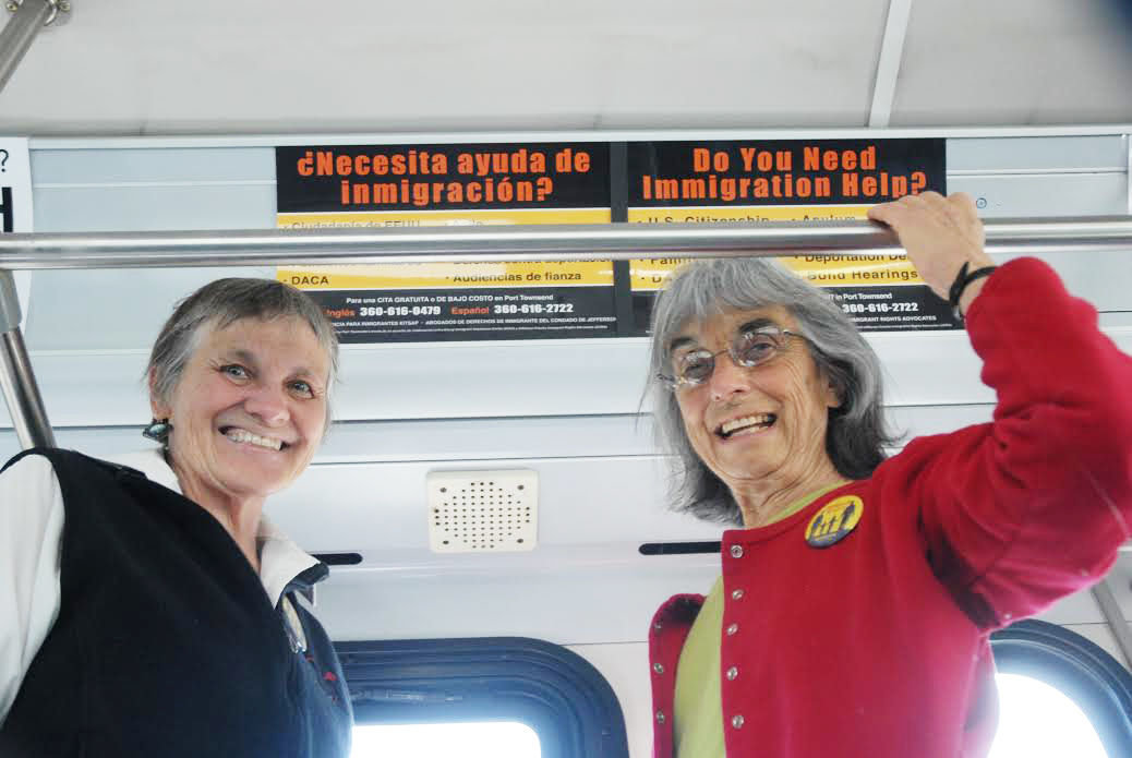 Katie Franco, left, and Libby Palmer leaders in the nonprofit Jefferson County Immigrant Rights Advocates group, stand in front of signs recently posted in Jefferson Transit buses. The signs, in both English and Spanish, advise people of a legal support system for immigrants in Jefferson County. 