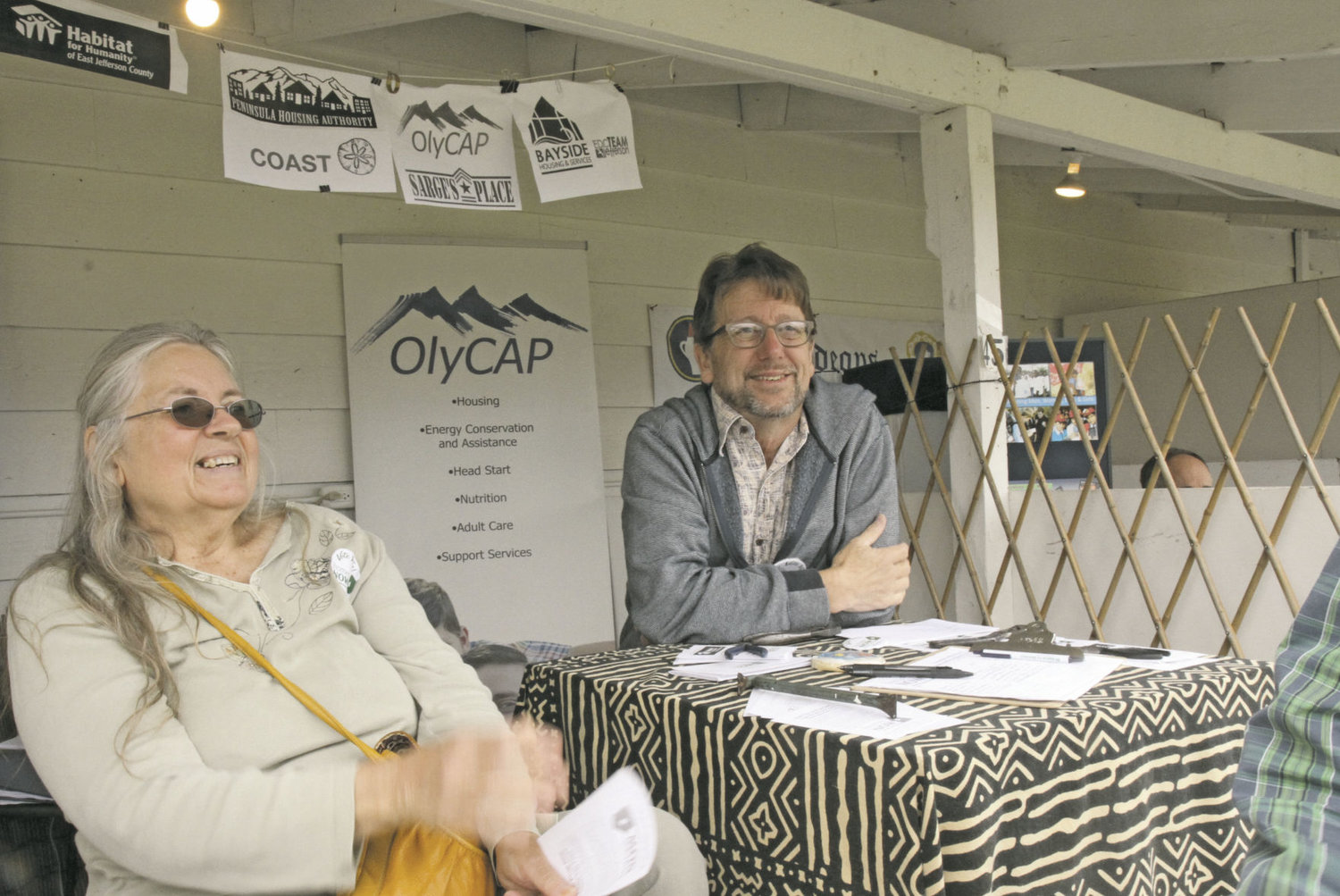 Pat Teal, who built a home through Peninsula Housing Authority’s self-help program (left), sits with Bruce Cowan (right) at a Homes Now booth at the Jefferson County Fair. The two talked to people about an upcoming proposition to raise property tax revenue as a means to support affordable housing projects in Jefferson County. Homes Now is the name of the political campaign advocating the passage of the proposal. Photo by Allison Arthur