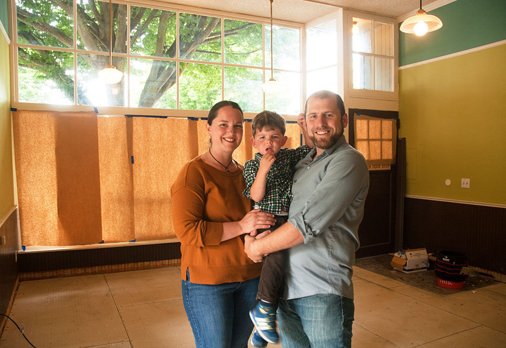 The owners of Finistère, Deborah Taylor and her husband, Scott Ross, stand inside their restaurant on July 20. With them is their 3-year-old son, Liam. Photo by Chris Tucker