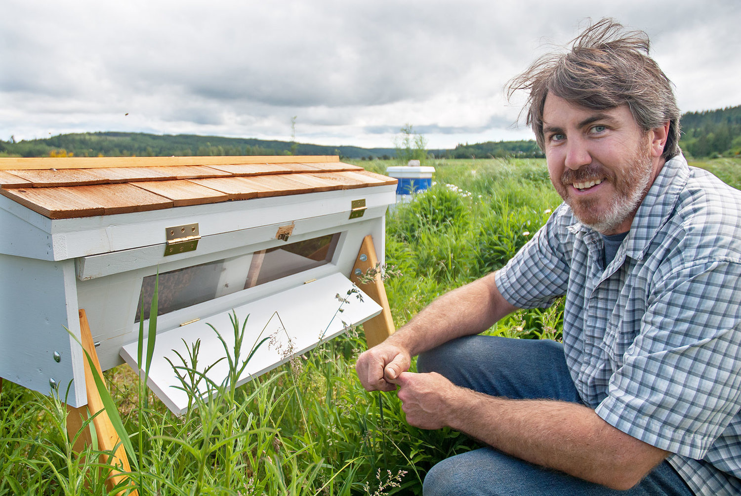 Chimacum High School teacher Gary Coyan, recently named as a Washington State Teacher of the Year, kneels next to the school’s top-bar beehive. Photo by Chris Tucker