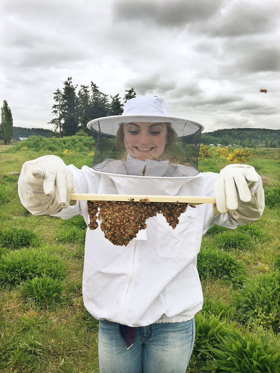 Student Rachel Smith wears a protective bee suit while holding some honeycomb. Photo courtesy Gary Coyan