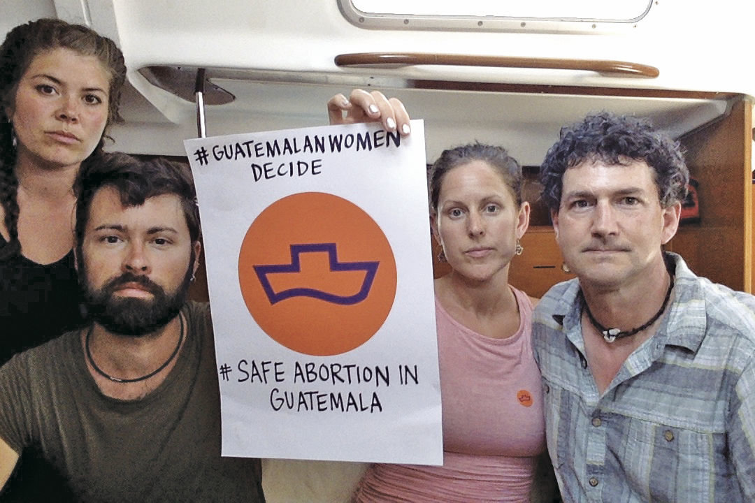 Merilee Nyland Evans (second from right) and Daniel Evans (far right) hold a poster in support of Women on Waves’ mission of providing abortion services in Guatemala. Also pictured (at left) are crew members Alecia Ott and Seth Bearden. The Evanses, who are from Port Townsend, are expected to return home March 3. Courtesy photo