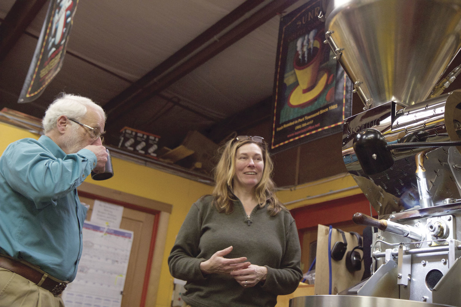 Earll Murman, left, listens as Sue Ohlson, co-owner of Sunrise Coffee in Port Townsend, explains the workings of a $100,000 coffee roaster, which Murman and other local investors helped her to purchase. The roaster also is helping to expand her business. Ohlson is scheduled to be one of the loan recipients to speak about LION (Local Investing Opportunities Network) on Saturday. Murman is a member of LION. Photo by Allison Arthur