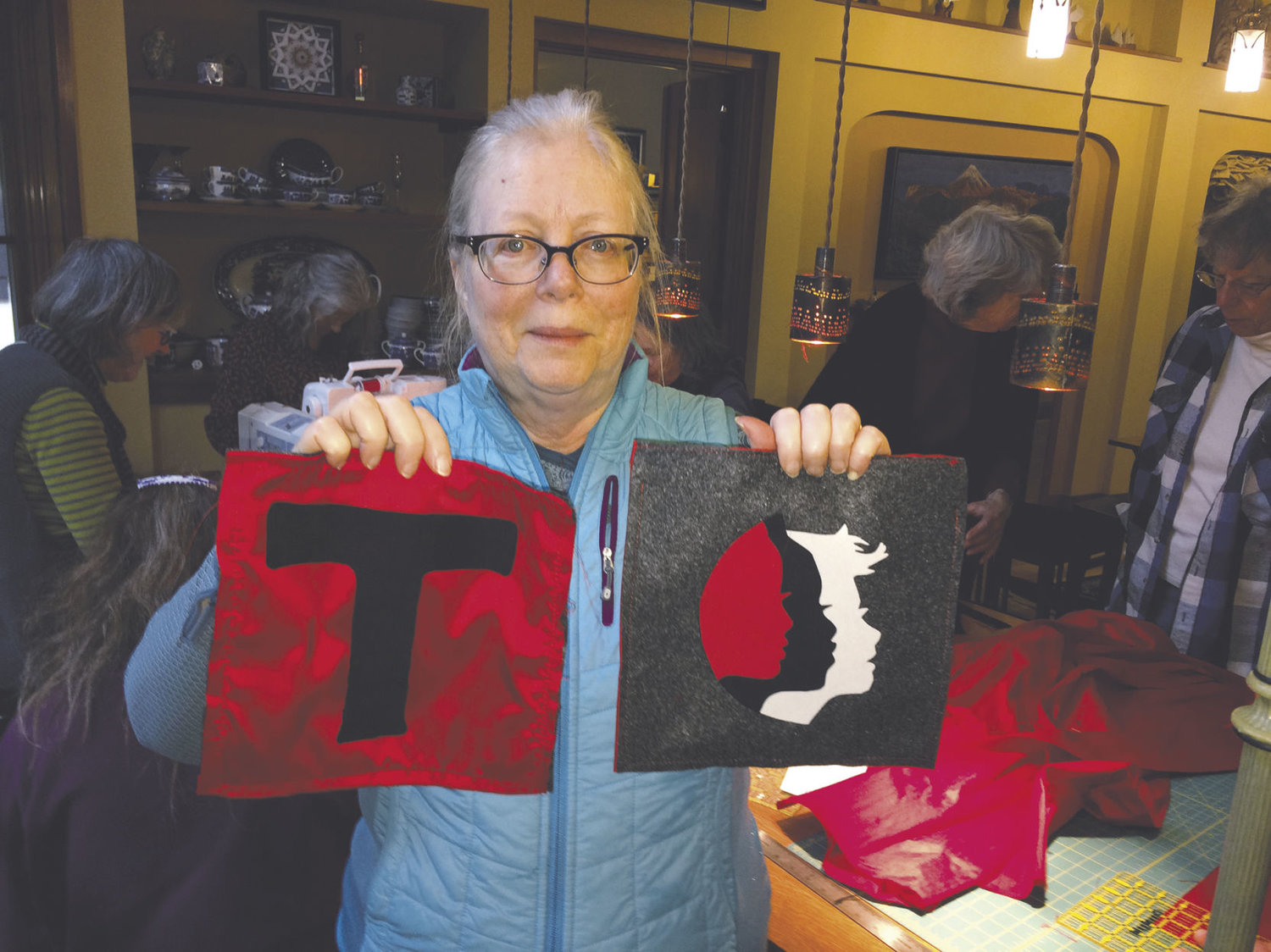 Anita Edwards holds up two blocks of a handmade sign she designed that is being made especially for a Seattle Womxn’s March on Saturday, Jan. 21. Women and men gathered Sunday, Jan. 8 at her home to help piece the sign together. Photo by Allison Arthur