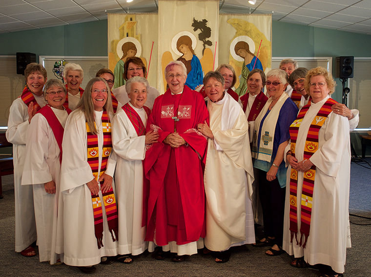 Roman Catholic Women Priests is an international group of devout Catholics founded in Germany in 2002 for the purpose of defying and changing a fundamental Catholic Church doctrine. Here, Bishop Olivia Doko (center, red) and members pose with newly ordained Judy Dahl (to Doko's left). Photo courtesy Leah Mitchell