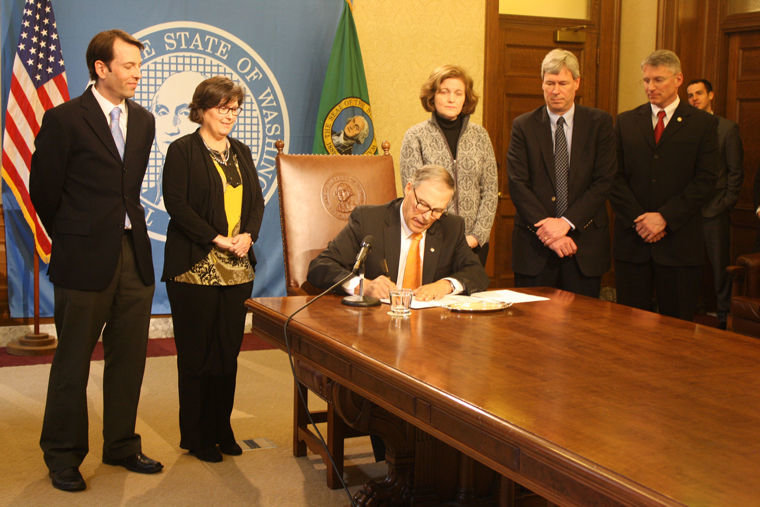 Washington Gov. Jay Inslee (center) signs SB 6195, which establishes a work group to create a plan to fully fund basic education. Standing from left are Sen. Andy Billig, Rep. Kristine Lytton, Sen. Christine Rolfes, Rep. Pat Sullivan, and Rep. Chad Magendanz. All were members of the eight-person work group that created the bill. Photo by Izumi Hansen