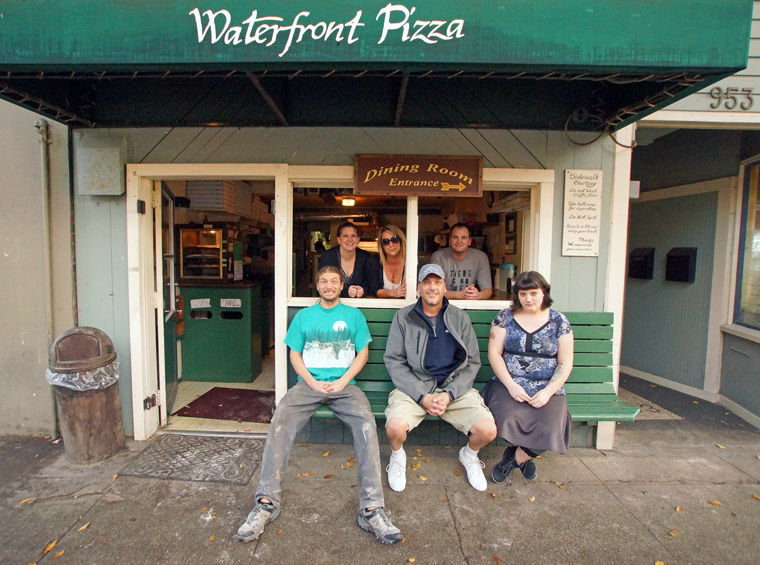 Waterfront Pizza employees (from left, front to back) Angelo Giangrosso, Mike Pruitt, Autumn Peterson, Jenn Pope, Mary Schultz and Paul Sale gather in the front window and bench of the restaurant's ground floor. Owner Diann Kuchera is not pictured. Photo by Nicholas Johnson