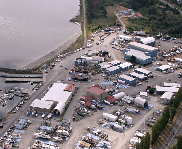 This photo taken during the 2012 Wooden Boat Festival (with Port of Port Townsend Boatyard property used as overflow parking from the nearby Haines Place Park-and-Ride) shows the Port Townsend Shipwrights Co-op headquarters (red-roofed buildings, center) in relation to the Townsend Bay Marine property (top, center). Leader file photo by Patrick J. Sullivan