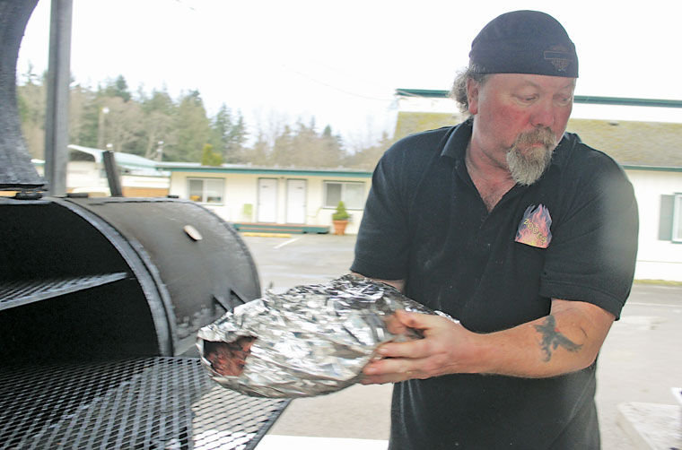 Bret “Zoog” Forsberg removes a brisket from his wood-fired barbecue smoker outside his restaurant in Port Hadlock. Now that he is allowed to speak about his business's appearance on the Food Network's "Restaurant Impossible" TV show, he said the remodeled building is cleaner, the kitchen is not as dirty as it was made out to be on TV, and there was no fault found with his style of barbecue. Photo by Patrick J. Sullivan