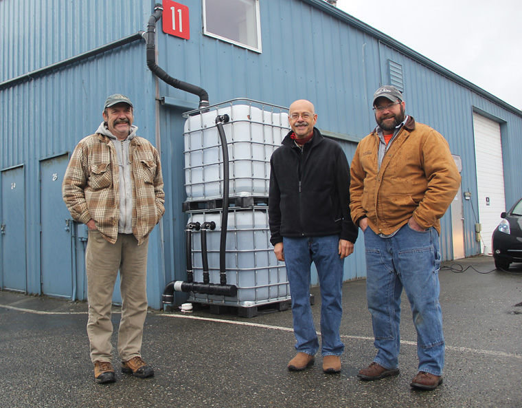 “Totes” filled with biochar filters are against this Port of Port Townsend building. Roof runoff is filtered this way before it goes to the Port’s stormwater system. Pictured are (from left) Port Maintenance Manager Larry Aase, engineer and entrepreneur Francesco Tortorici and Al Cairns, Port environmental compliance officer. Photo by Scott Wilson