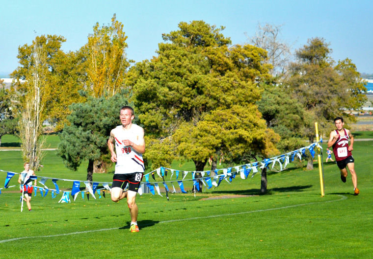 Port Townsend High School senior Ryan Clarke was running in sixth place when he kicked into another gear with a half mile to go, and ran past the pack to win the 2014 state 1A cross-country title. Here, with 300 meters to go, Clarke (left) has the lead on Graham Peet and Andrew Ayres, the top two state placers from 2013. Photo by Kim Clarke
