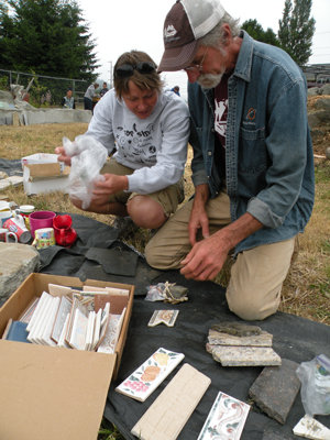 Shannon Burns of Port Townsend chats with Wayne Chimenti about items she brought to put on Al Nejmeh’s memorial bench, which is in a garden behind Farm’s Reach Café along State Route 19 in Chimacum. Photo by Allison Arthur