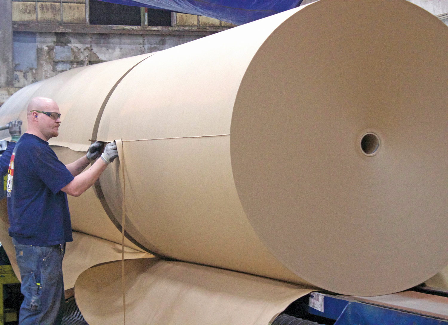 Scott Brown cuts the excess ends off a giant roll of brown paper made at the Port Townsend Paper Company.