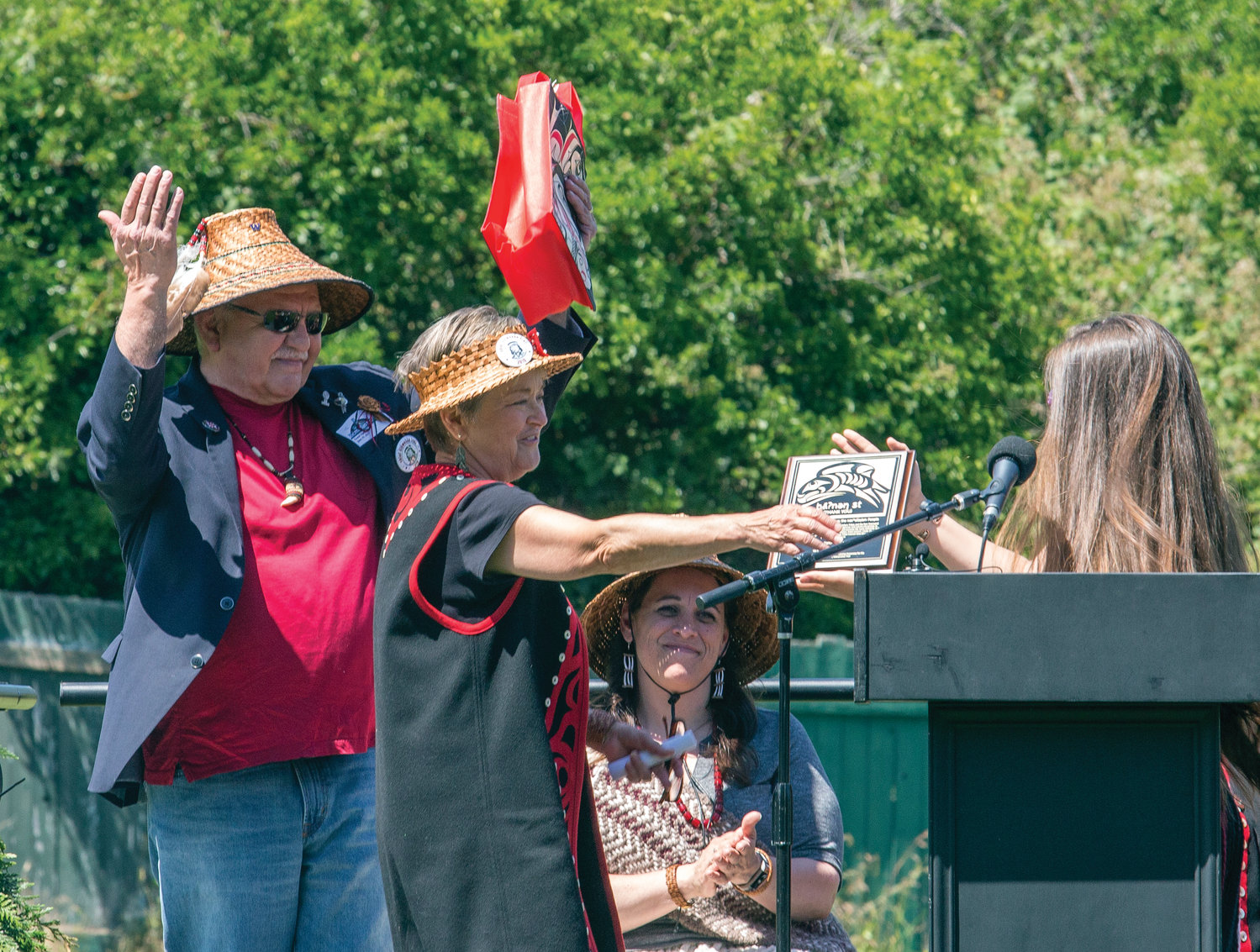 Ron Allen raises his arms high to celebrate, as Celeste Dybeck receives recognition for her contribution to the číčməhán (Chetzemoka) trail during its June 29 grand opening.
