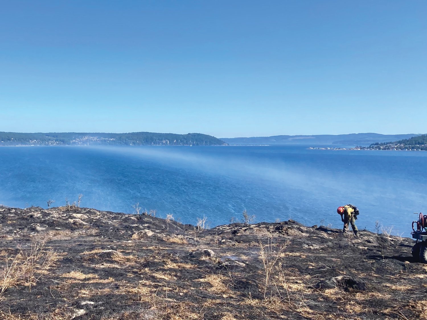Firefighters work on extinguishing smoldering areas on Protection Island following the initial blaze.