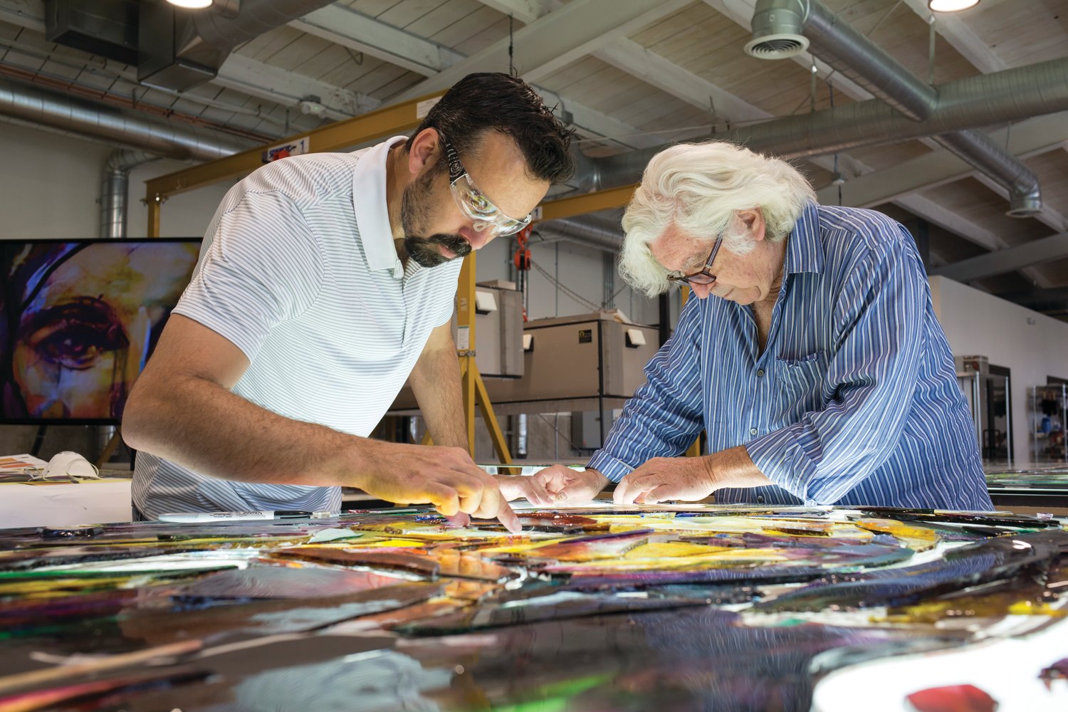 In this still from “Holy Frit,” Tim Carey and Narcissus Quagliata arrange bits of glass for a fused panel that would become part of a stained-glass triptych as large as a basketball field.