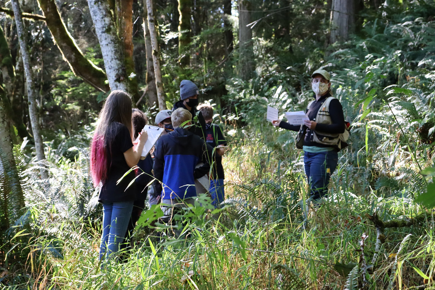Quilcene students jot down notes as Jefferson Land Trust’s Snow Creek Forest Preserve manager Carrie Clendaniel lends a hand for student fieldwork education.