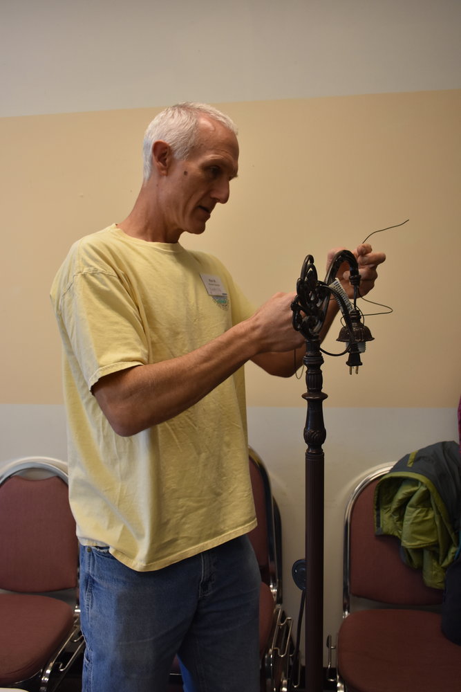Ron Moller looks at the wiring for a lamp during a Repair Cafe.