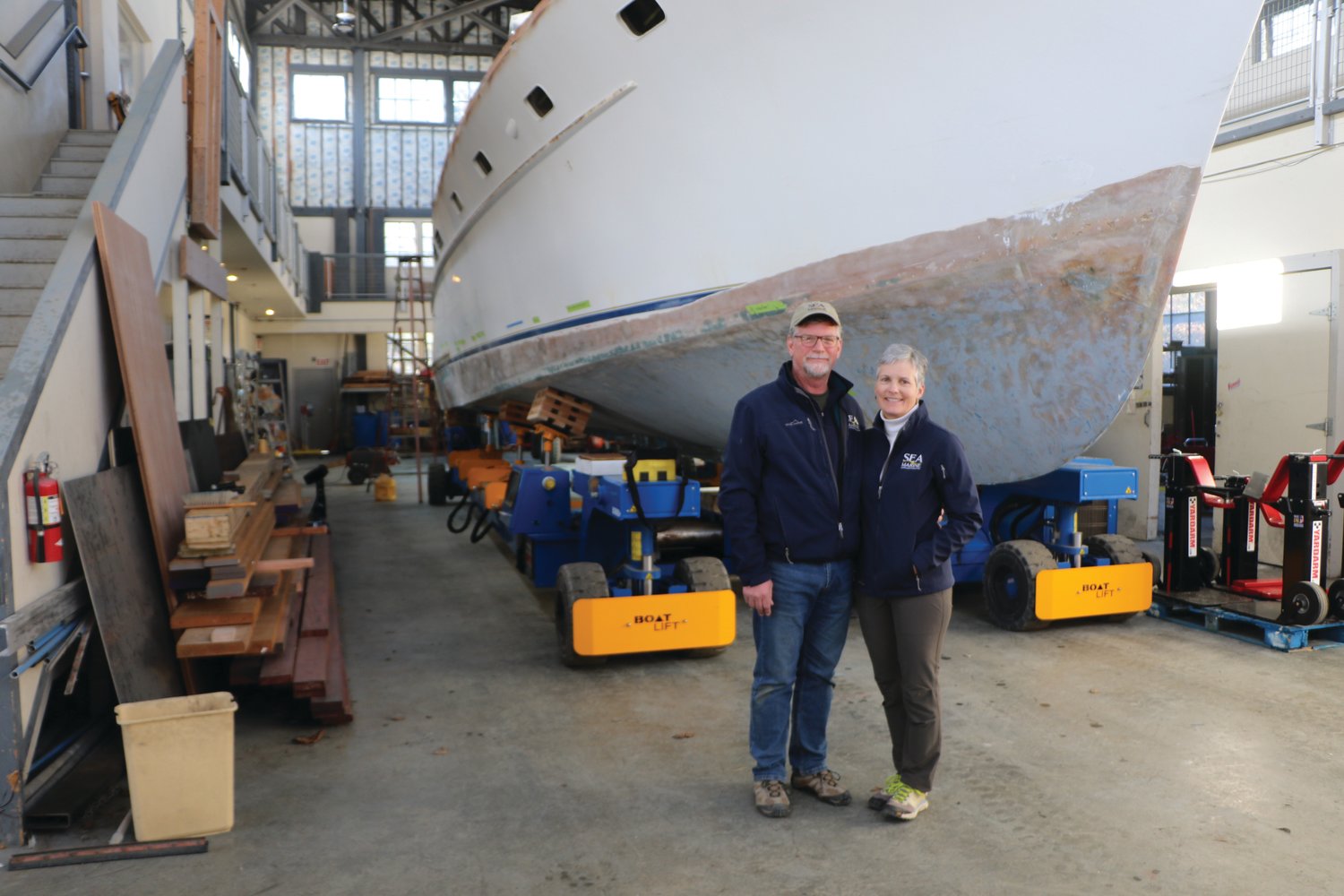 Pat and Sara Shannon, co-owners of SEA Marine, stand before their historic Rybovich yacht, mid-restoration.