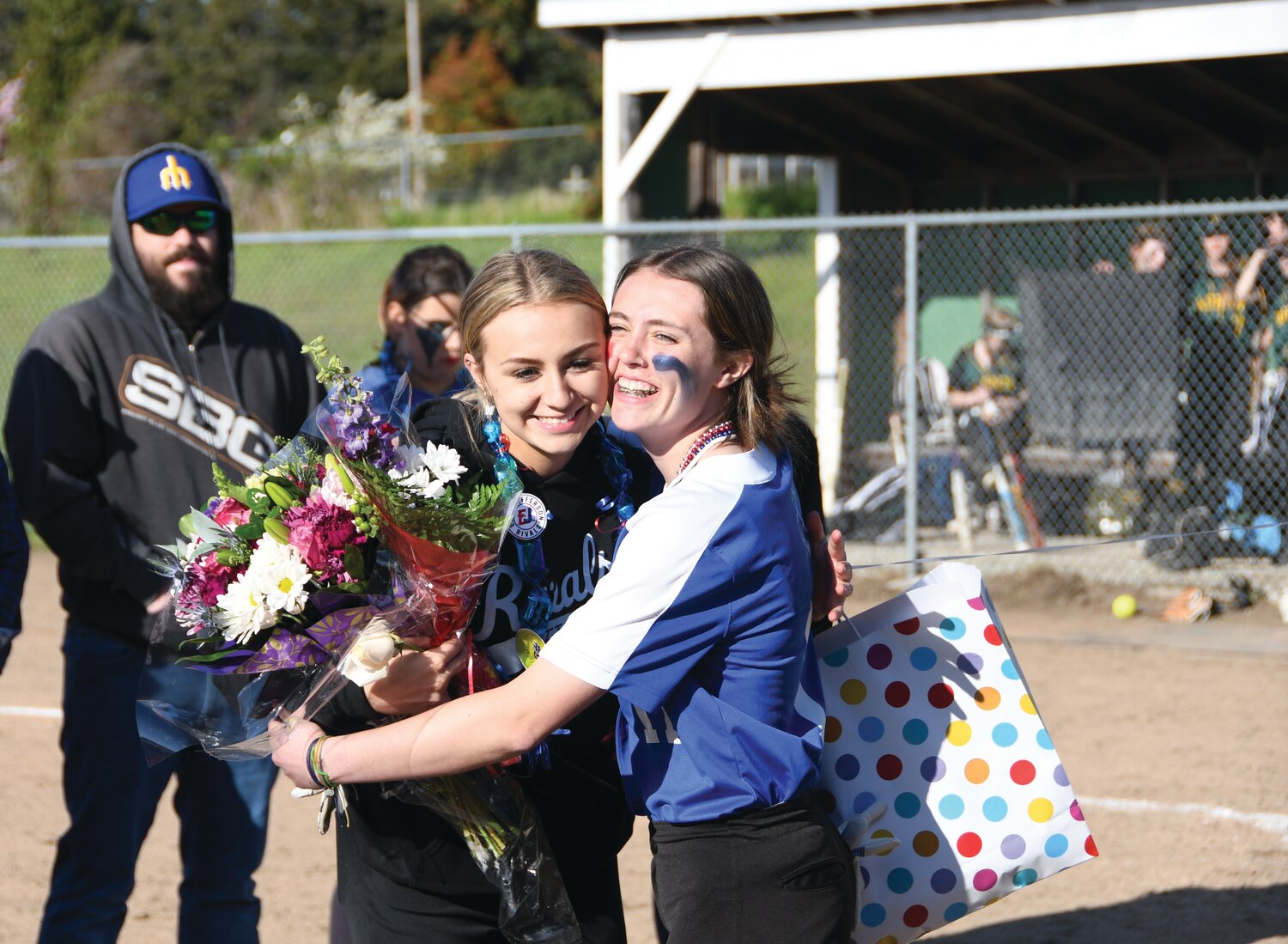 In between the double header games and during the senior celebration ceremony, senior Macy Aumock shares a hug with Rylee Spainhower-Oas before receiving her flowers.