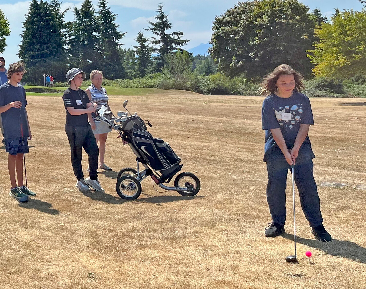 Archer McGriff prepares to drive the ball while Eliot Minartin, Shawn Williams, and Instructor Wanda Synnestvedt watch.